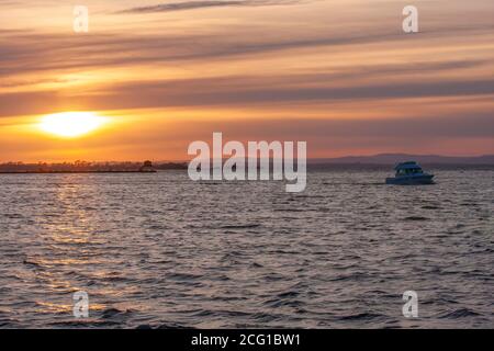 Motorcruiser auf Süßwassersee segelt zum Yachthafen bei Sonnenuntergang Über Lough Neagh bei Oxford Island County Armagh auf einer Frühlingsabend in Nordirland Stockfoto