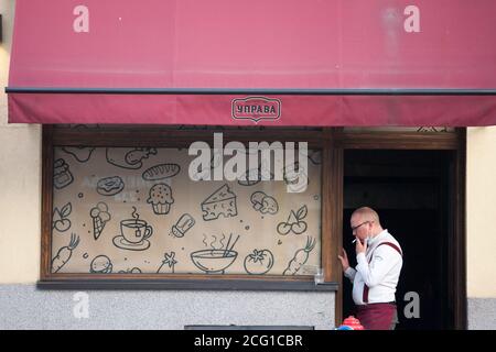 BELGRAD, SERBIEN - JAUGUST 20, 2020: Kellner, ein Kellner in Uniform, mit einer Pause Rauchen Tabakzigarette trägt eine Atemmaske während der Stockfoto