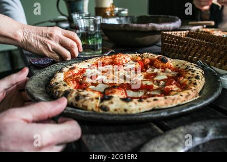 Person, die Pizza aus dem Holzofen in einem Restaurant in Japan serviert Stockfoto