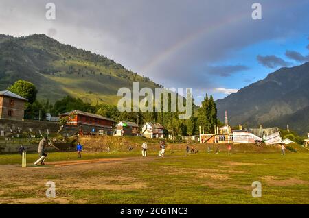 Srinagar, Indien. September 2020. Ein Regenbogen wird gesehen, wie Jungen Cricket spielen in Gagangir, etwa 80 km von Srinagar, der Sommerhauptstadt von Jammu und Kaschmir. Kredit: SOPA Images Limited/Alamy Live Nachrichten Stockfoto