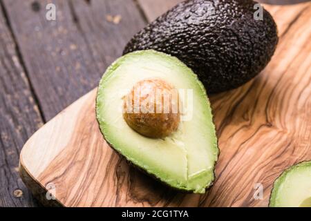 Zwei Haas Avocado Früchte auf Holzhintergrund. Avocado in Scheiben schneiden Stockfoto