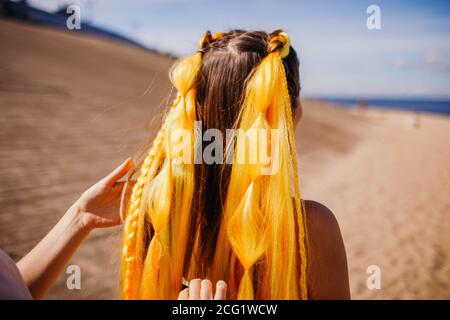 Gelber Kanekalon mit Zöpfen auf der Frau.Sonniger Sommertag am Strand. Stockfoto