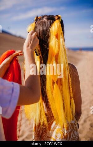 Gelber Kanekalon mit Zöpfen auf der Frau.Sonniger Sommertag am Strand. Stockfoto