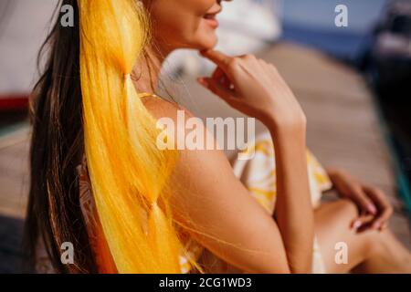 Gelber Kanekalon mit Zöpfen auf der Frau.Sonniger Sommertag am Strand. Stockfoto