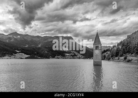 Schöne Schwarz-Weiß-Ansicht der Spitze des alten Glockenturms von Graun, der aus dem Wasser des Reschensee, Südtirol, Italien, hervortritt Stockfoto