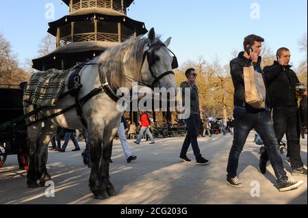 20.03.2015, München, Bayern, Deutschland, Europa - die Menschen sprechen am Telefon, während sie am Chinesischen Turm im Englischen Garten vorbeigehen. Stockfoto