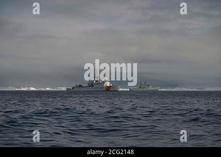 USCGC CAMPBELL wagte sich mit der HDMS KNUD RASMUSSEN in die Disko Bay für gemeinsame Helikoptertrainingsübungen. Disko Bay ist bekannt für seine starke Konzentration an großen Eisbergen, die vor dem Jacobshavn-Gletscher abkalben. Der Jacoshavn-Gletscher ist der Hauptfaktor für Eisberge in Baffin Bay und der Labradorsee. CAMPBELL navigierte sicher die schwere Konzentration von schwimmenden Eis, Eisberge von der Größe professioneller Sportstadien und startete ihr OTH-Cutter-Boot zum Training. CAMPBELL startete auch ihren MH-65 Hubschrauber, um Hebezeug, Rettungskorb und Landungen/Starts vom KNUD RASMUSSEN durchzuführen. Stockfoto