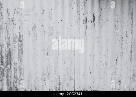 Verzinktes Blech mit weißer Farbe lackiert. Leere weiße Wand Textur Hintergrund. Abblätternde Farbe an der weißen Wand. Verzerrtes graues galvanisiertes Blech. Stockfoto