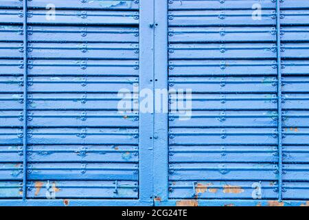 Lackierte gewellte Metallstruktur. Abstrakter Hintergrund in blauer Farbe mit Metallnieten gemalt Stockfoto