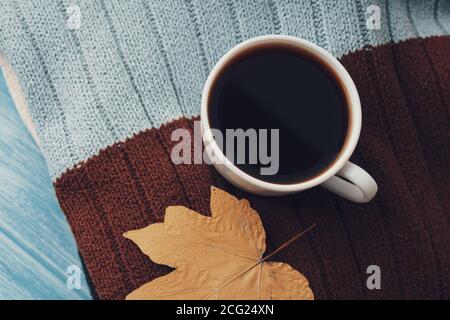 Warmer Schal, Herbstblätter und heiße dampfende Tasse Kaffee. Stockfoto