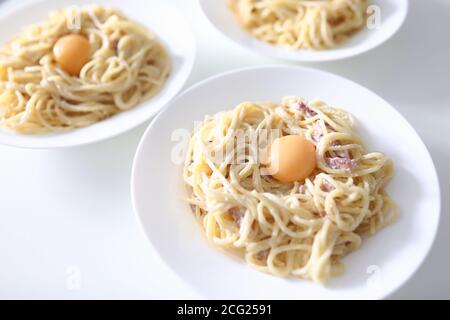 Auf dem Tisch sind drei Teller Spaghetti Carbonara mit pochiert Eigelb Stockfoto