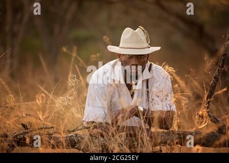 afrikanischer Gentleman im afrikanischen Busch mit Buschhut in Das Gras Stockfoto