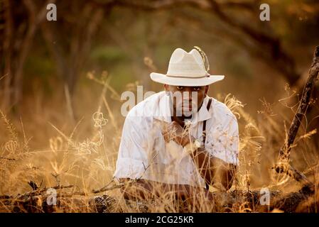 afrikanischer Gentleman im afrikanischen Busch mit Buschhut in Das Gras Stockfoto