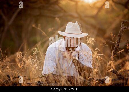 afrikanischer Gentleman im afrikanischen Busch mit Buschhut in Das Gras Stockfoto