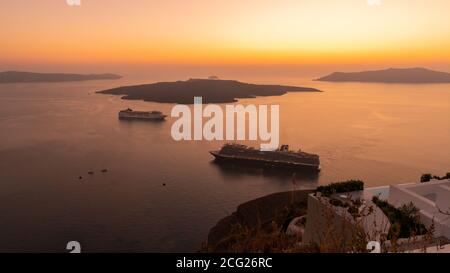 Fira, Santorini, Griechenland - 14. Oktober 2019: Wunderschöne Sonnenuntergänge und Ausblicke auf Kreuzfahrtschiffe vor Anker, von einem beliebten Aussichtspunkt in Fira auf der Stockfoto