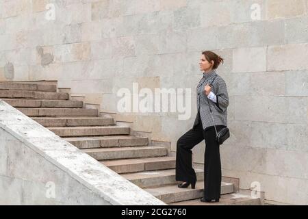 Geschäftsfrau klettert eine Betontreppe auf Stadtmauer Hintergrund. Erfolgreiches Frauenkonzept. Speicherplatz kopieren Stockfoto