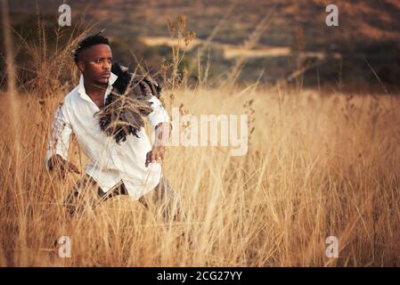 afrikanischer Gentleman im afrikanischen Busch mit Buschhut in Das Gras Stockfoto