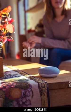 Frau im Gespräch mit Smart Speaker zu Hause Stockfoto