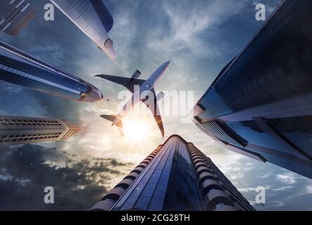 Low-Angle-Ansicht des fliegenden Verkehrsflugzeugs über Wolkenkratzern. Stockfoto