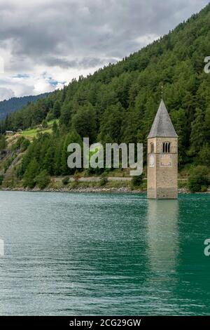 Schöne vertikale Ansicht der Spitze des alten Glockenturms von Graun, der aus dem Wasser des Reschensee, Südtirol, Italien, hervortritt Stockfoto
