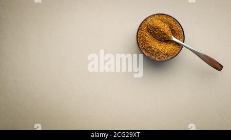 Brauner Zucker mit Schüssel und Löffel auf dem Hintergrund für Text Stockfoto