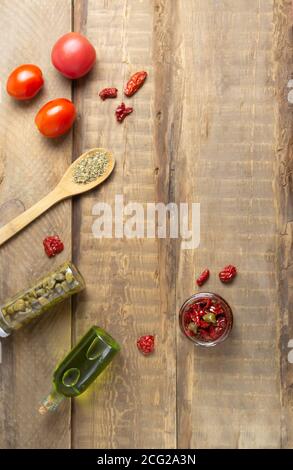 Sonnengetrocknete Tomaten in einem Glas mit Gewürzen auf Holzgrund. Draufsicht. Speicherplatz kopieren. Stockfoto