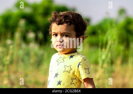 Ein trauriges kleines indisches Kind, das wütend auf die Kamera schaut, asiatische Kinder in der Natur Stockfoto