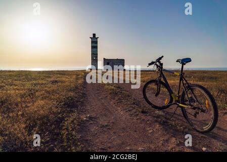 Ein alter Leuchtturm am Rande des Meeres, in den Strahlen der untergehenden Sonne. Stockfoto