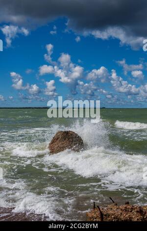 Das Wasser spritzt um den großen Stein an der Küste der Ostsee. Stockfoto