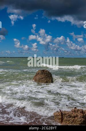 Das Wasser spritzt um den großen Stein an der Küste der Ostsee. Stockfoto