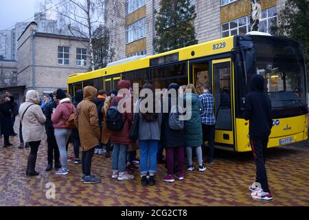 Eine Gruppe junger Jungen und Mädchen, die vor dem Schulbus stehen, ist bereit, loszuwerden. März 2020. Kiew, Ukraine Stockfoto