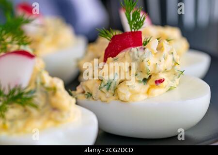 Ein Bild von frisch zubereiteten gekochten Eiern gefüllt mit Mayo, Zwiebeln, Ei und Rettich garniert mit Dill. Stockfoto