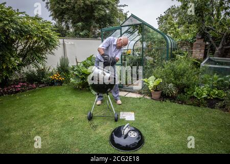 Rentnerpaar in den 80er Jahren genießen das Leben im Freien Grillen und Essen gesundes Gemüse aus eigenem Anbau während der Coronavirus Lockdown, Somerset, Großbritannien Stockfoto