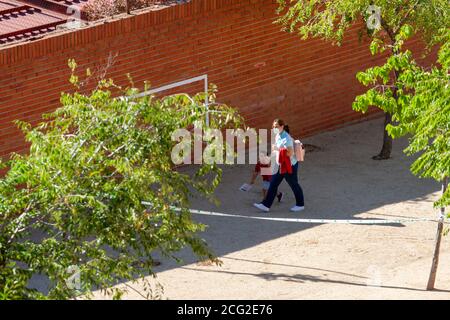 Toledo, Spanien. September 2020. Eine Mutter, die eine Gesichtsmaske trägt, um COVID-19 zu vermeiden, hält die Hand ihres Sohnes während des ersten Schultages. Stockfoto