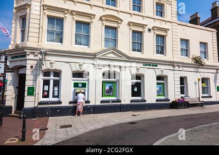 Eine Frau zieht Bargeld von einem Geldautomaten in Lloyds Bank Gebäude in Sandwich, Kent, Großbritannien Stockfoto