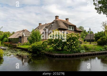 Giethoorn, Niederlande - 28. August 2020: Häuser und Boot am Kanal Stockfoto