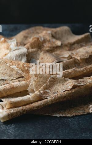 Hausgemachtes dünnes armenisches Pita-Brot (Lavasch) liegt auf einem dunkelblauen Steingrund. Selektiver Fokus. Stockfoto
