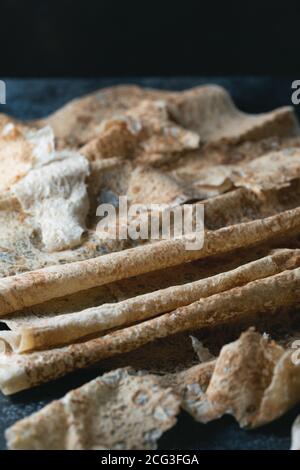 Hausgemachtes dünnes armenisches Pita-Brot (Lavasch) liegt auf einem dunkelblauen Steingrund. Selektiver Fokus. Stockfoto