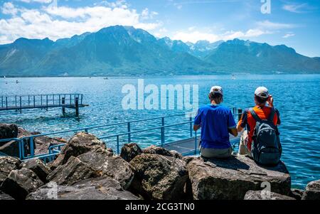 Zwei unkenntlich Touristen bewundern die Aussicht auf den Genfer See und Die Alpen an der Küste von Montreux in der Waadtländer Schweiz Stockfoto