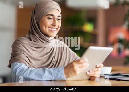 Schöne muslimische Frau sitzt im Café, mit digitalen Tablet Stockfoto