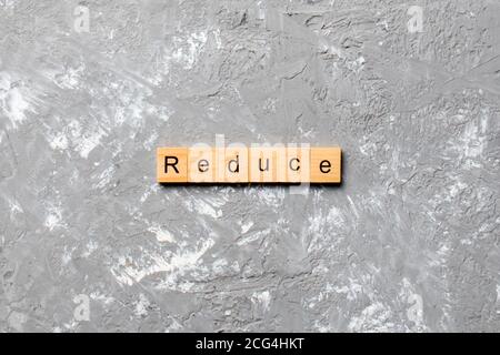 Reduzieren Sie Wort auf Holzblock geschrieben. Reduzieren Sie Text auf Zementtisch für Ihr Design, Konzept. Stockfoto