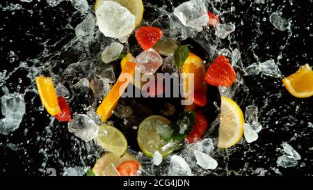 Frostbewegung der Frucht mit Eiswürfeln und Wasserspritzern, isoliert auf schwarzem Hintergrund Stockfoto