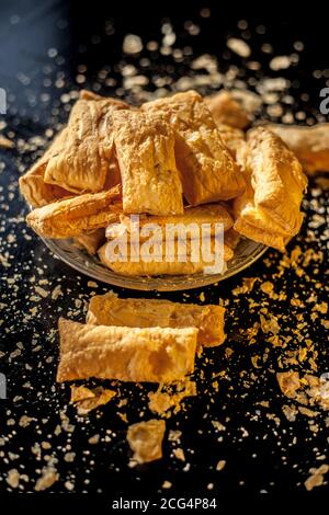 Klassisches Jeera Khari oder Blätterteig in einer Glasplatte auf einer schwarzen Oberfläche. Ein Schuss frisch gebackener Blätterteig-Snack auf einem Servierteller. Stockfoto