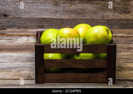 Holzkiste mit reifen grünen Äpfeln auf Holztisch. Stockfoto