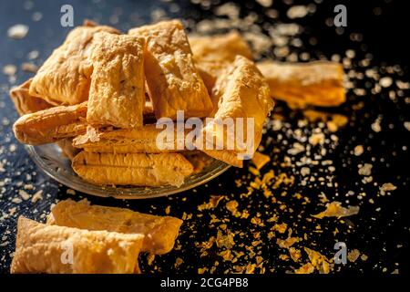 Klassisches Jeera Khari oder Blätterteig in einer Glasplatte auf einer schwarzen Oberfläche. Ein Schuss frisch gebackener Blätterteig-Snack auf einem Servierteller. Stockfoto