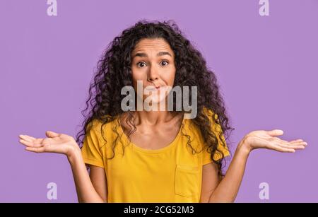 Ich weiß es nicht. Zweifelhafte Brünette Frau Zuckende Schultern Über Purple Studio Hintergrund Stockfoto