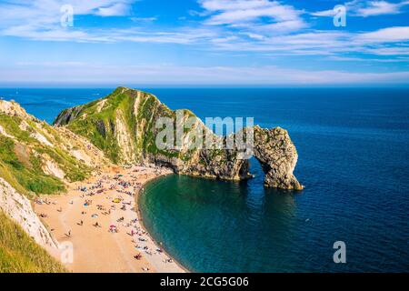 Sonnenanbeter am Nachmittag am Strand an der berühmten Durdle-Tür An der Jurrasic Küste von Dorset im Südwesten England, Großbritannien Stockfoto