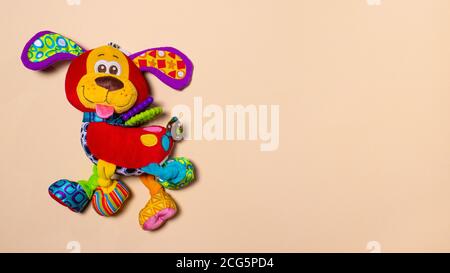 Rot orange doggy Spielzeug auf einem beigen Hintergrund mit Platz für Text. Weiches Plüsch Spielzeug für Baby Hund Banner für Spielzeugladen. Stockfoto