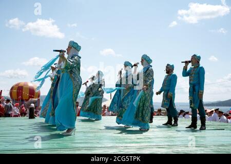 Das Ensemble in russischen Volkstrachten singt auf einer Promenade Bühne, am Ufer des Großen Sees, auf dem Karatag Musikfestival. Region Krasnojarsk. Rus Stockfoto