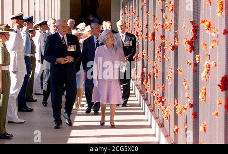 Die britische Königin Elizabeth II. Geht in Begleitung des australischen Kriegshelden Major General 'Digger' James (L) am National war Memorial in Canberra an einer Mauer der Erinnerung vorbei. Stockfoto